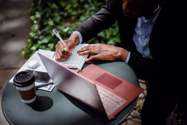 Man taking notes in planner while working remotely in cafe with laptop. Photo by Ketut Subiyanto from pexels.com