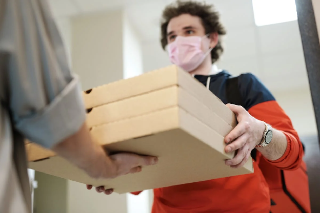 Man Wearing a Face Mask Delivering Pizza. Photo by Norma Mortenson on pexels.com