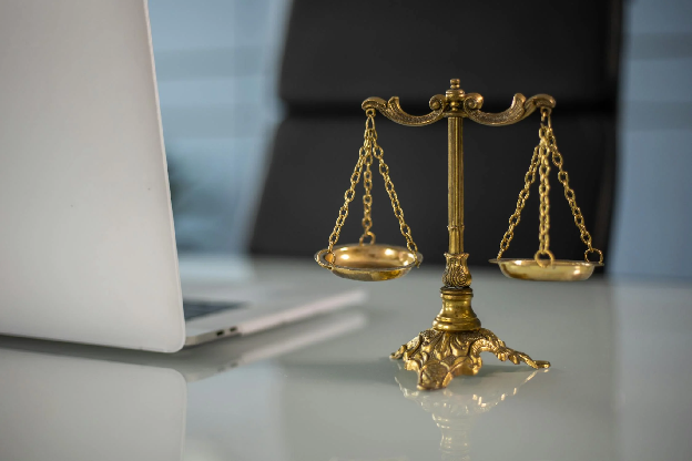 Golden justice scales on a desk beside a laptop, symbolizing law and balance. Stock Photo. Photo by KATRIN BOLOVTSOVA on Pexels.com