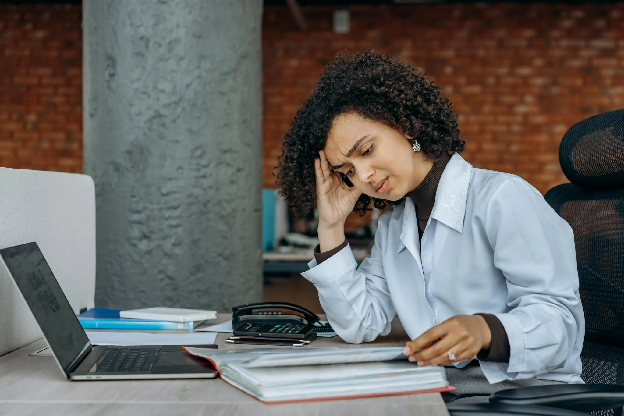 Business woman experiencing fatigue while working on financial paperwork at her desk. Stock Photo. Photo by Mikhail Nilov on pexels.com