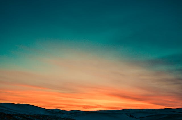 Picture of the sun setting by a hill side. Photo by NO NAME on pexels.com.