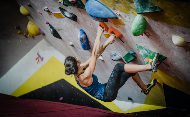Woman rock climbing inside building. Photo by yns plt on Unsplash