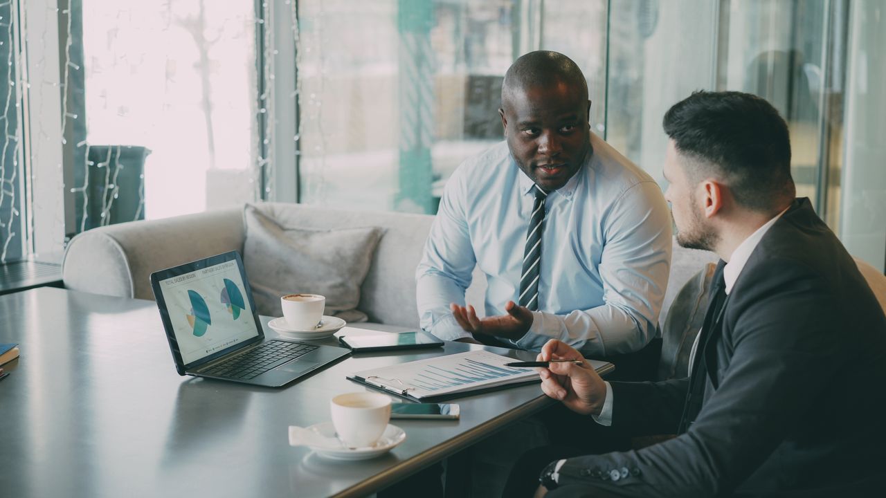 Two business professionals engaged in discussion over laptops and documents. Photo by 3 Vitaly Gariev on pexels.