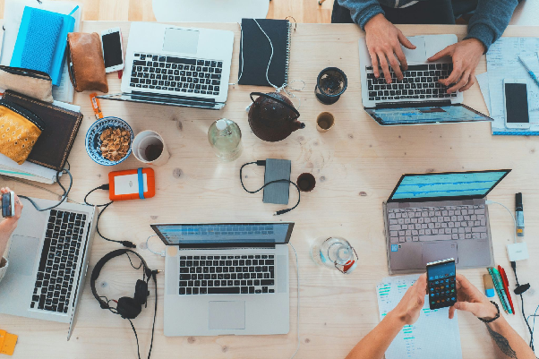 Work desk with laptops, headsets, hard drives and phones.