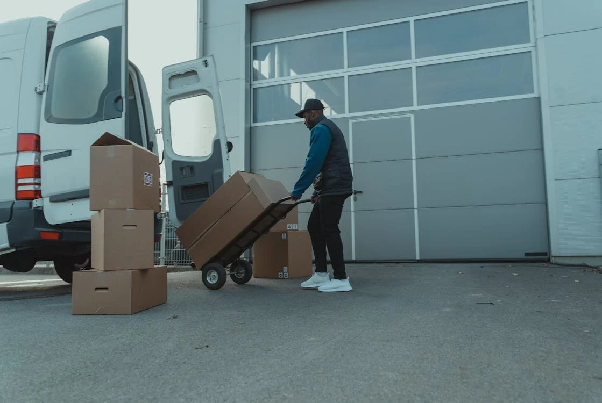 Delivery Man pulling a Trolley with Carton Boxes. Photo by Tima Miroshnichenko on pexels.com