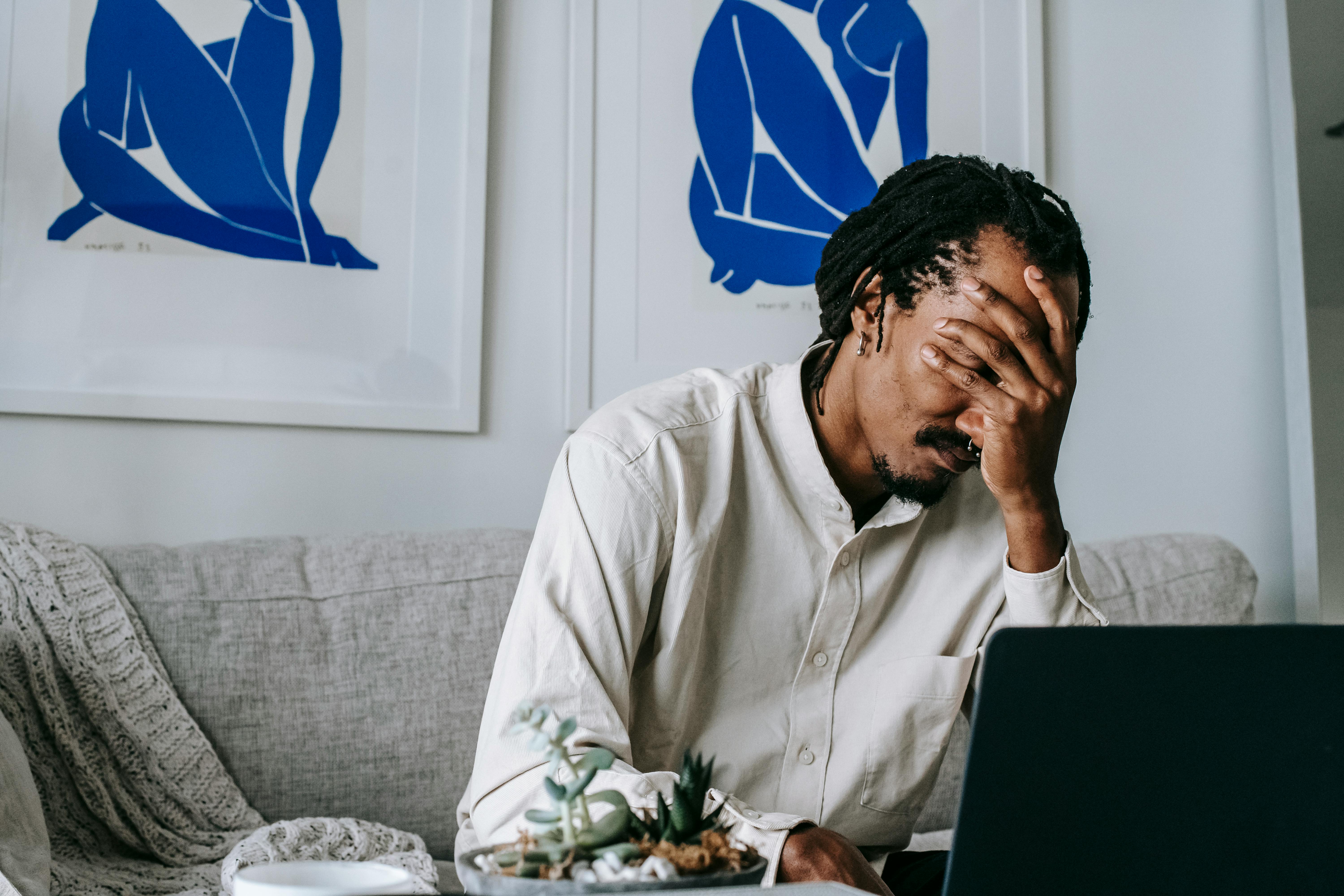 Upset young black guy covering face with hand while working remotely on netbook. Photo by Alex Green on pexels.com